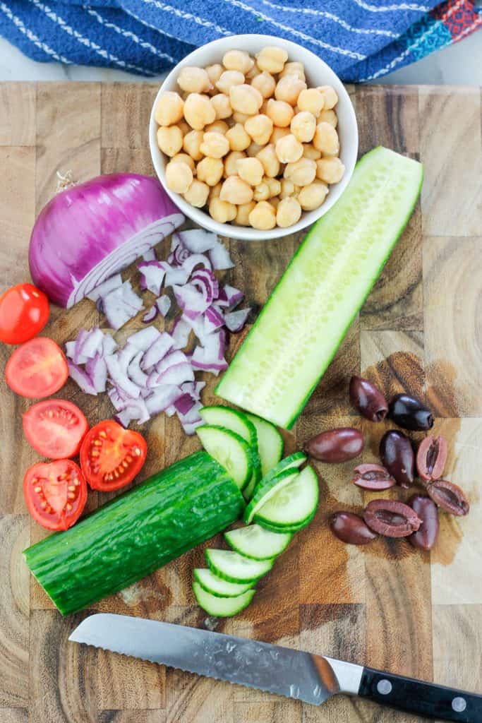 Overhead shot of chopped veggies and bowl of chickpeas for grain bowl recipe.