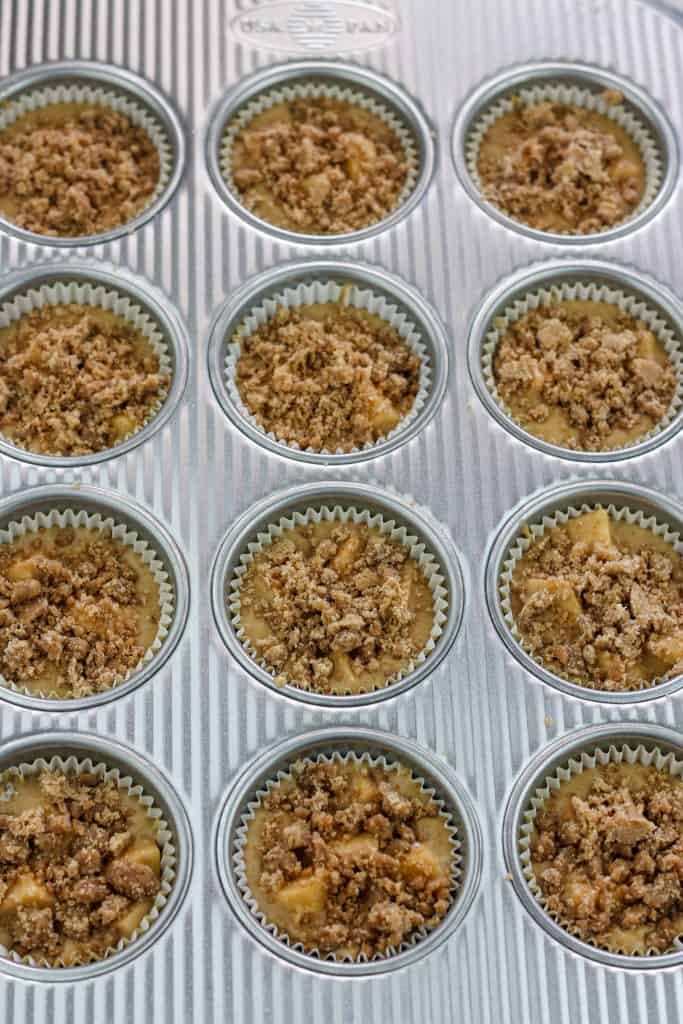 Overhead shot of uncooked chai apple muffins in pan topped with crumble topping.