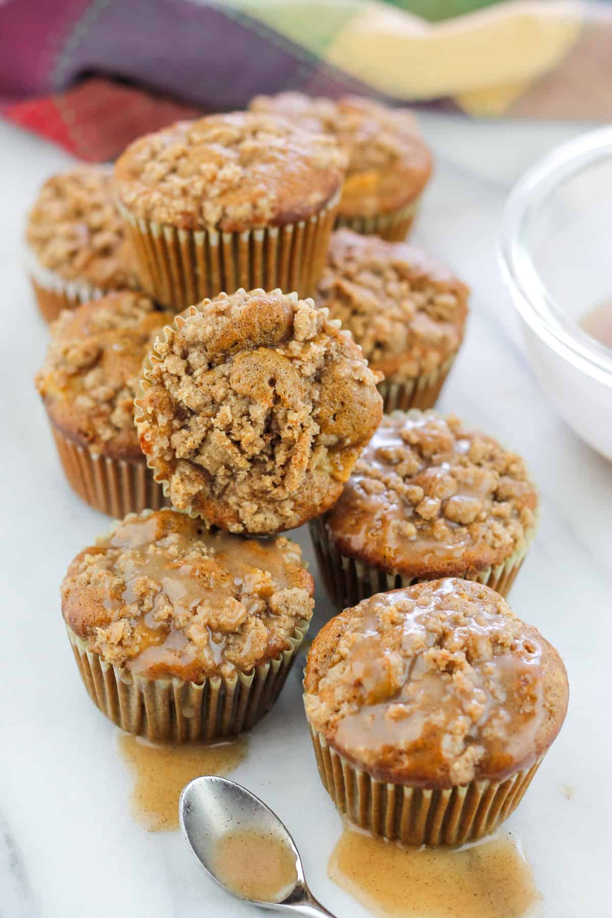 Shot of chai apple crumble top muffins on counter with two muffins stacked on top of muffins.