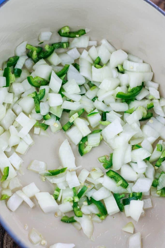 Overhead shot of chopped onions, and chopped jalapeños in dutch oven.