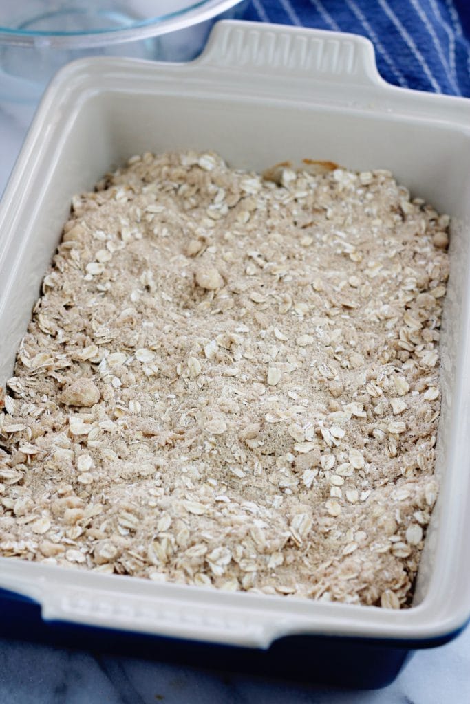 Unbaked apple crisp with the topping over the apples in a rectangle baking dish.