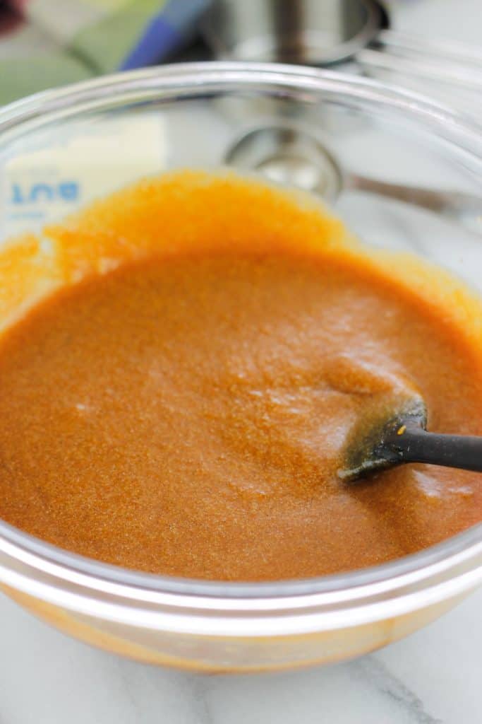 Wet ingredients mixed together in a glass bowl with a spatula in the bowl.