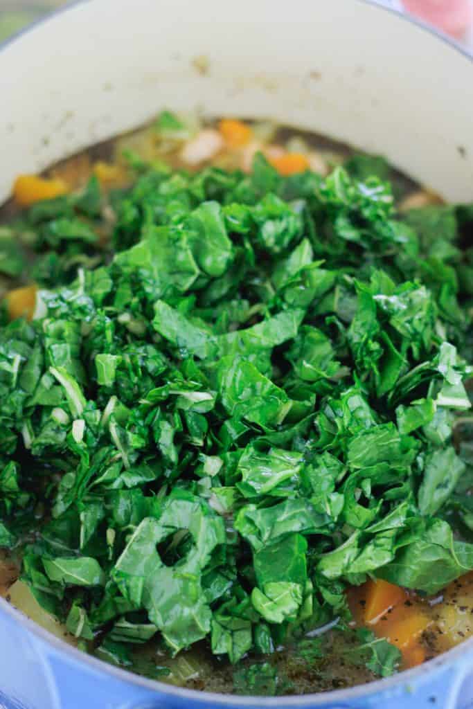 Chopped swiss chard added to the pot of soup.