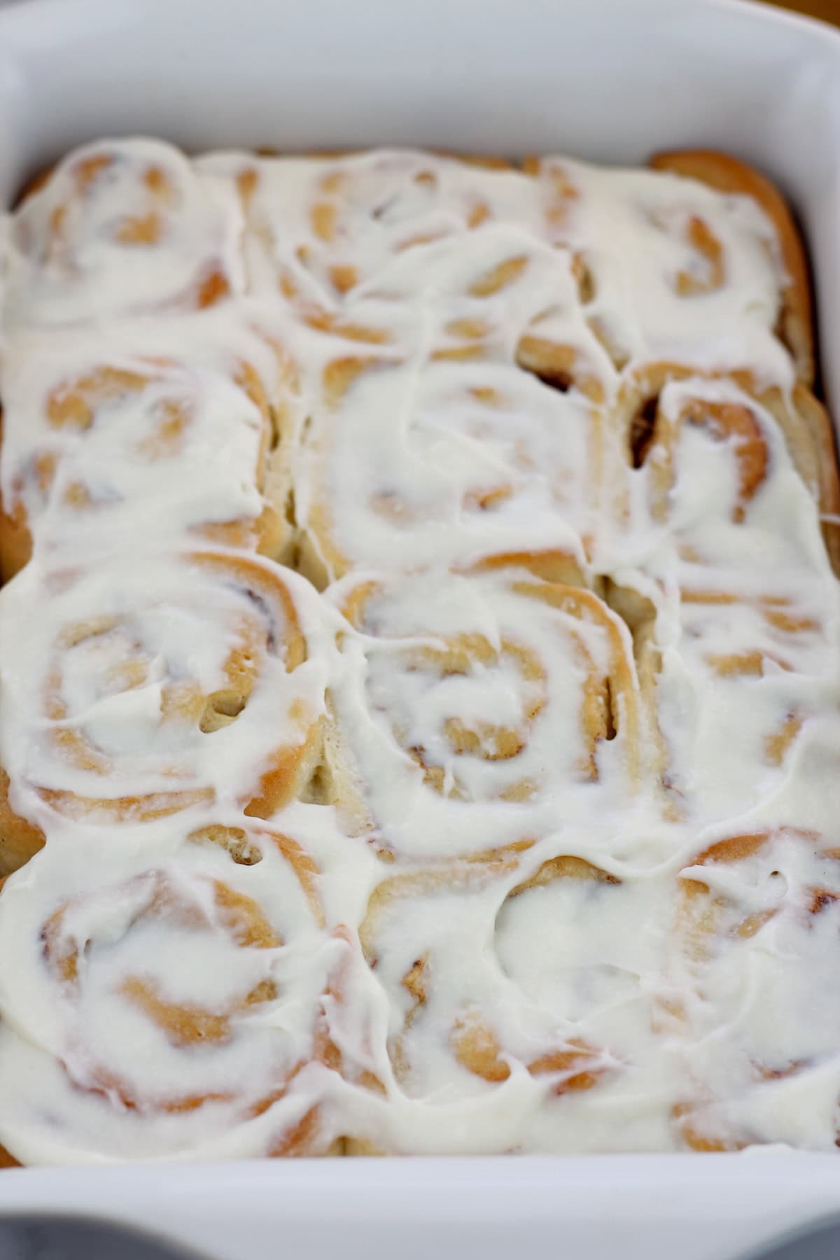 Shot of baked caramel apple cinnamon rolls with cream cheese topping.