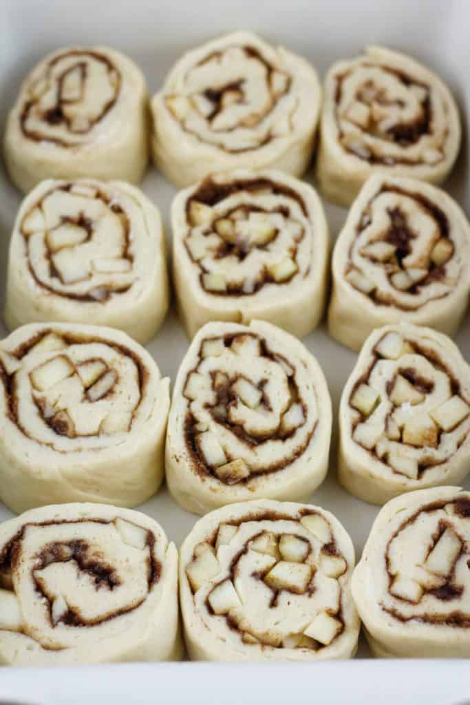 Shot of unbaked caramel apple cinnamon rolls in a baking dish.