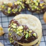 Chocolate Dipped Pistachio Nut cookies on a cooling rack, stacked.