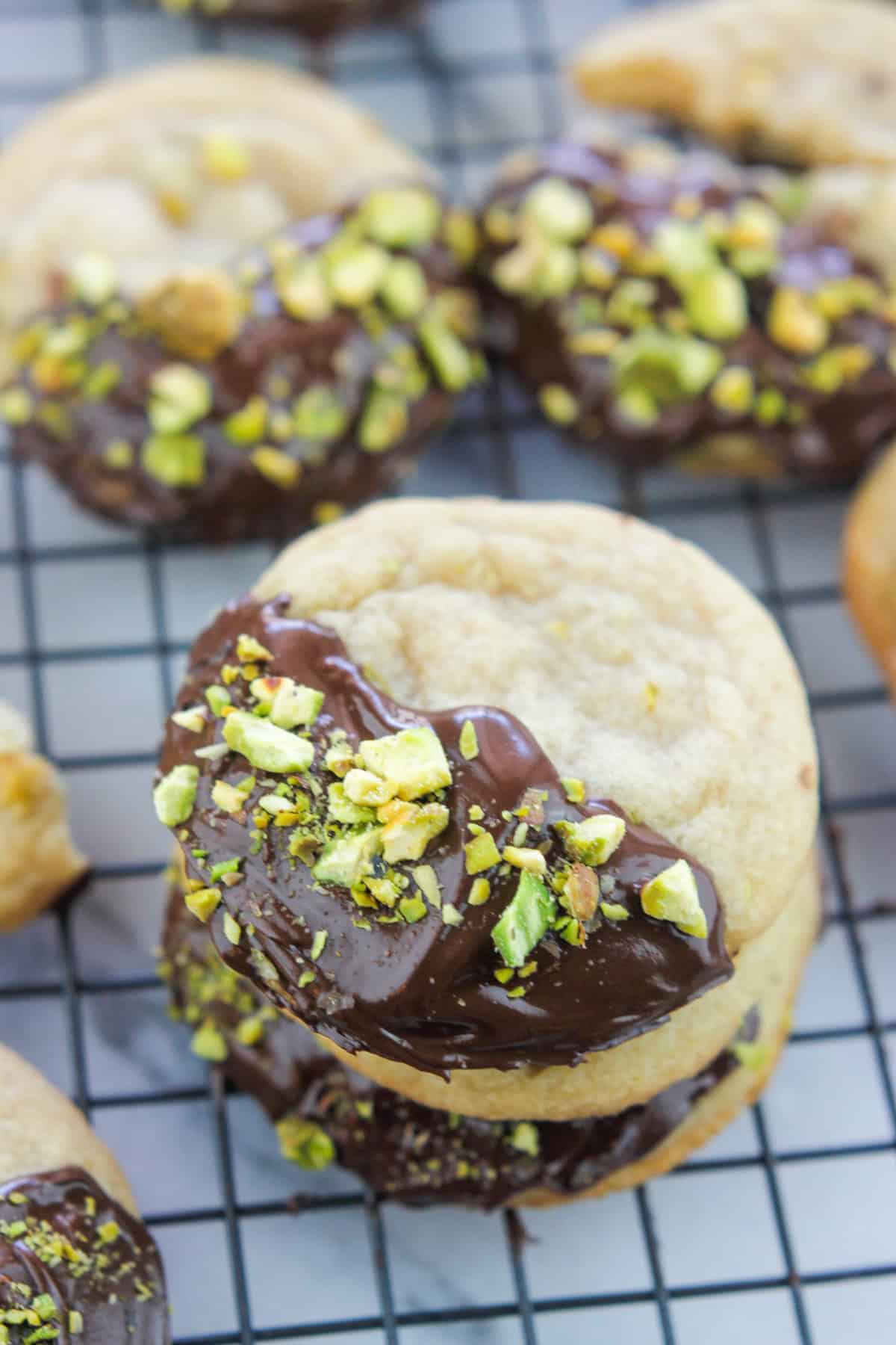 Chocolate Dipped Pistachio Nut cookies on a cooling rack, stacked.