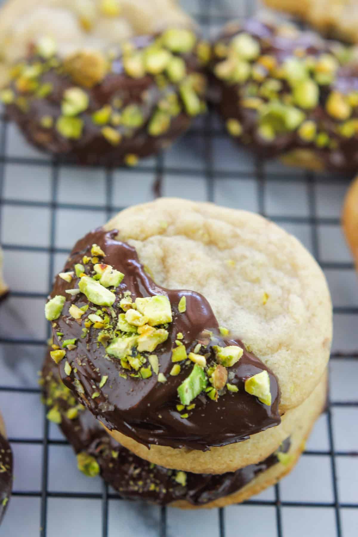 Chocolate Dipped Pistachio Nut cookie on a cooling rack, stacked.