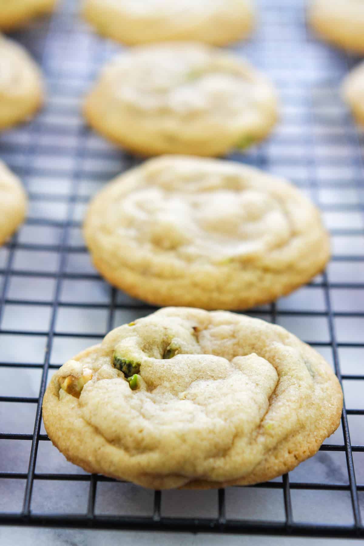 Close-up of baked chocolate dipped pistachio nut cookies in a cooling rack.