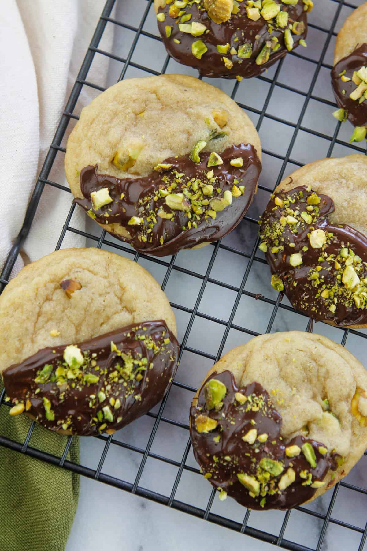 Overhead shot of Chocolate dipped Pistachio nut cookies on a cooling rack.