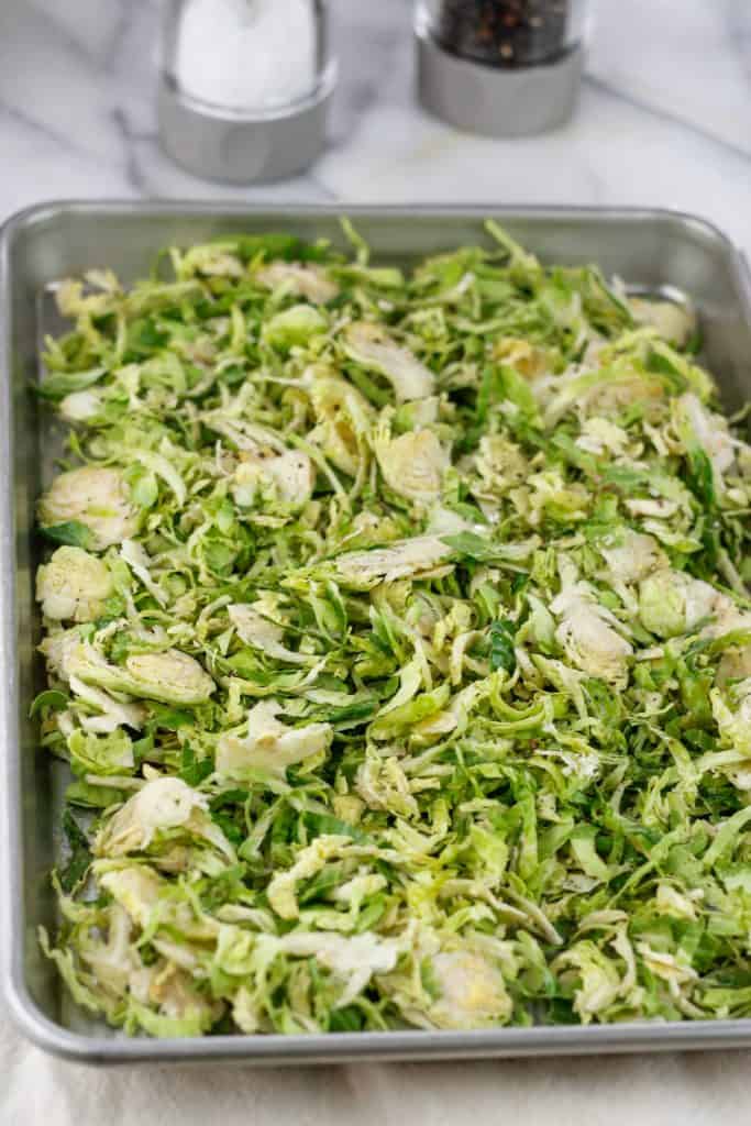 Uncooked shaved brussels sprouts on a baking pan.