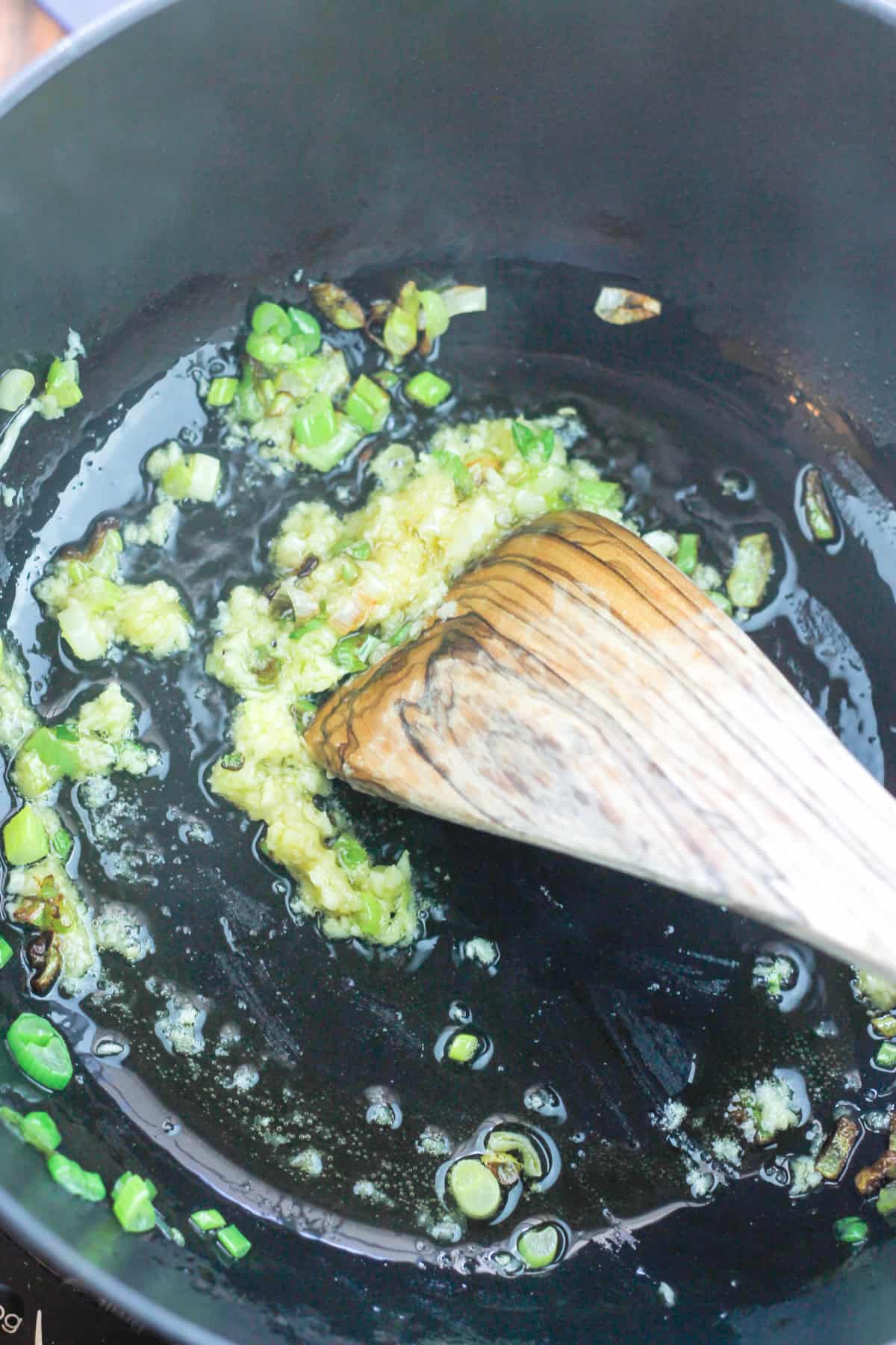 Sliced green onions, minced garlic and ginger in a dutch oven.