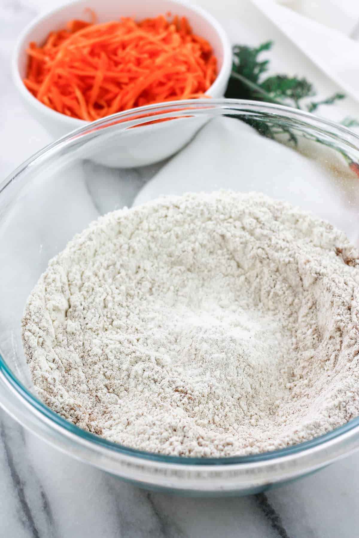 Dry ingredients for the carrot cake in a glass bowl.