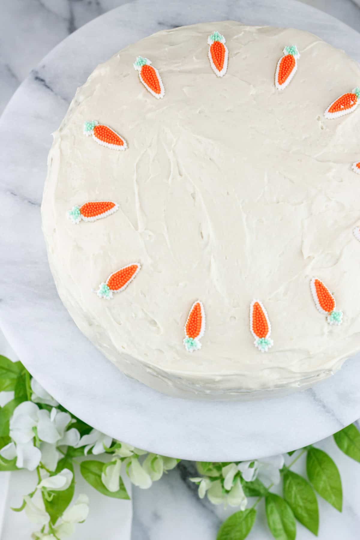 Overhead shot of iced carrot cake with carrot decorations.