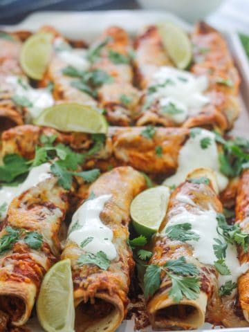Close-up of a platter of baked chipotle chicken taquitos.