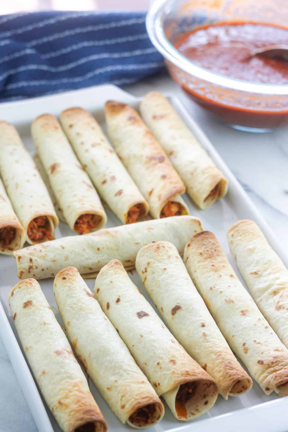 Crispy baked chipotle chicken taquitos on a baking platter.