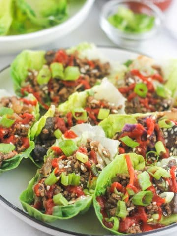Platter of Low-Carb Asian-Style Ground Meat Lettuce Wraps with extra lettuce in platter in back