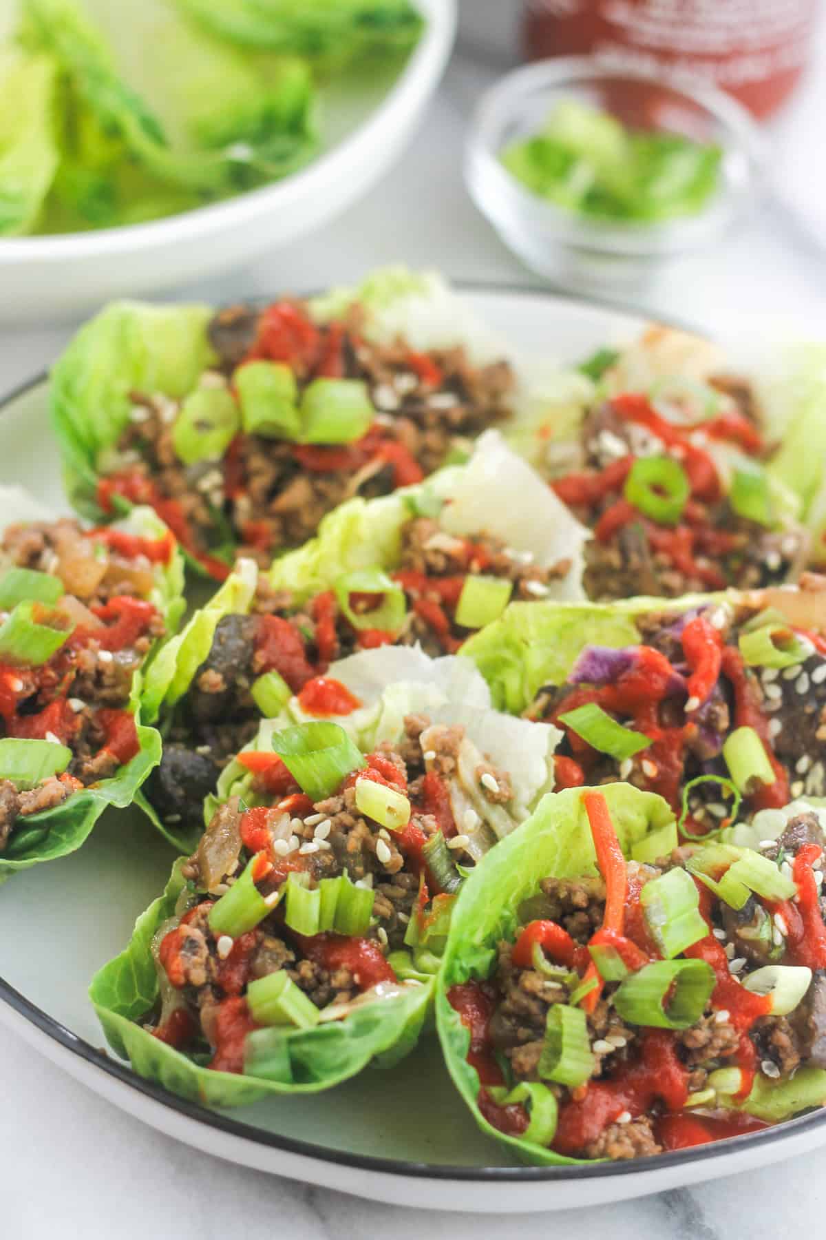 Platter of Low-Carb Asian-Style Ground Meat Lettuce Wraps with extra lettuce in platter in back
