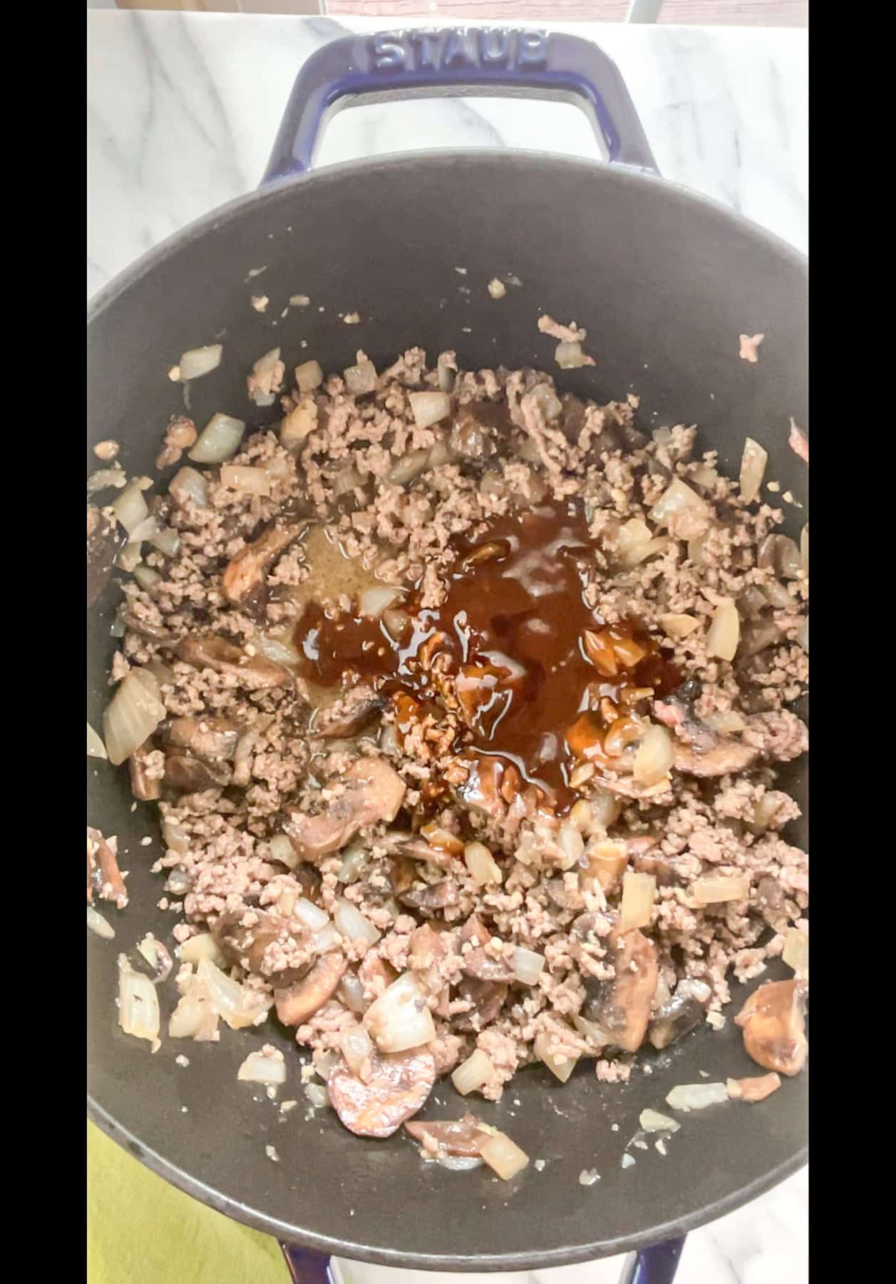 Seasoned browned ground meat in pan with sauce added to pan.
