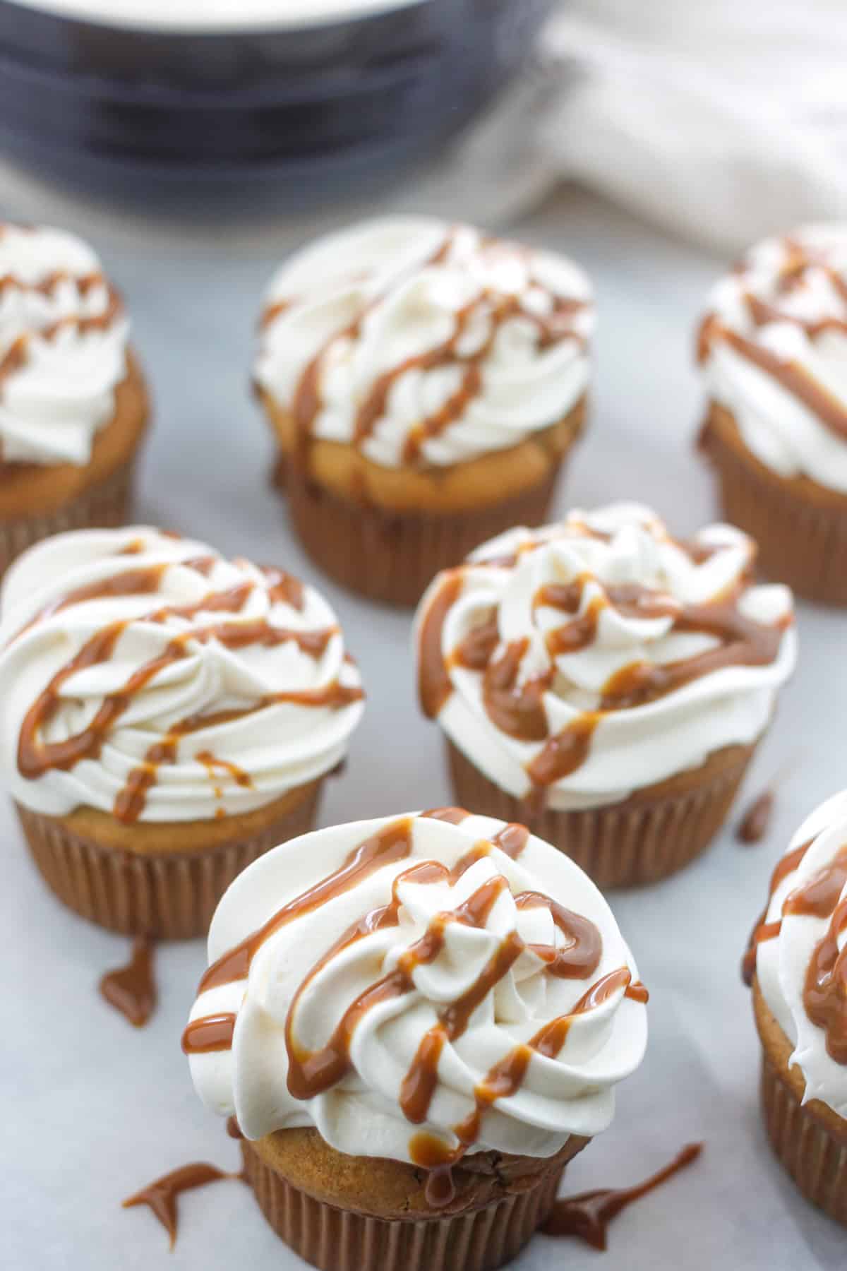 Apple cider cupcakes with cream cheese frosting drizzled with caramel sauce.