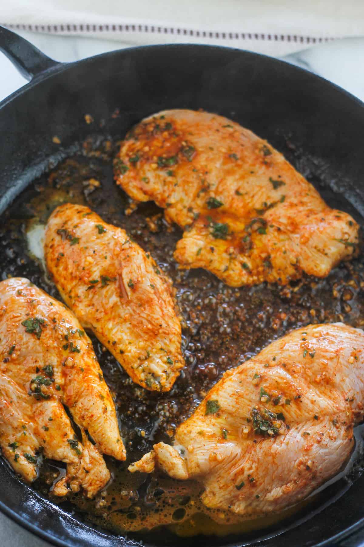 Boneless chicken breast cooking in cast iron braiser