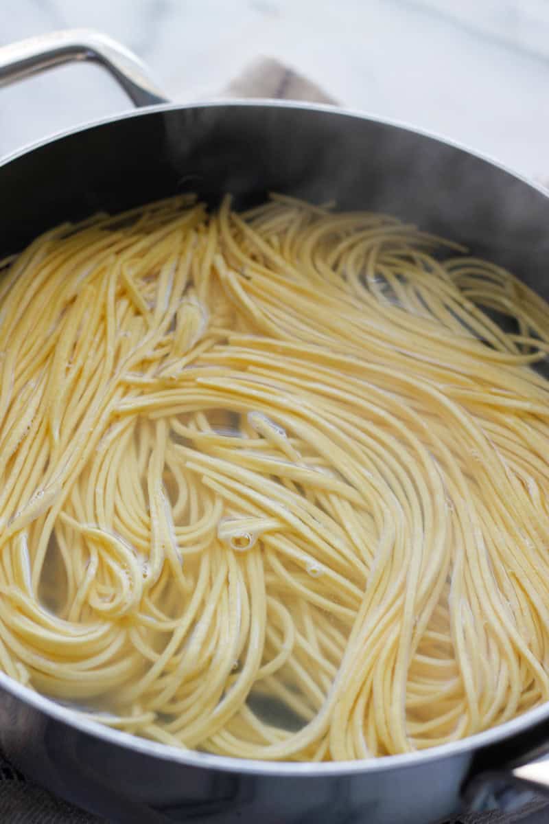Packaged refrigerated pasta cooking in boiling water.