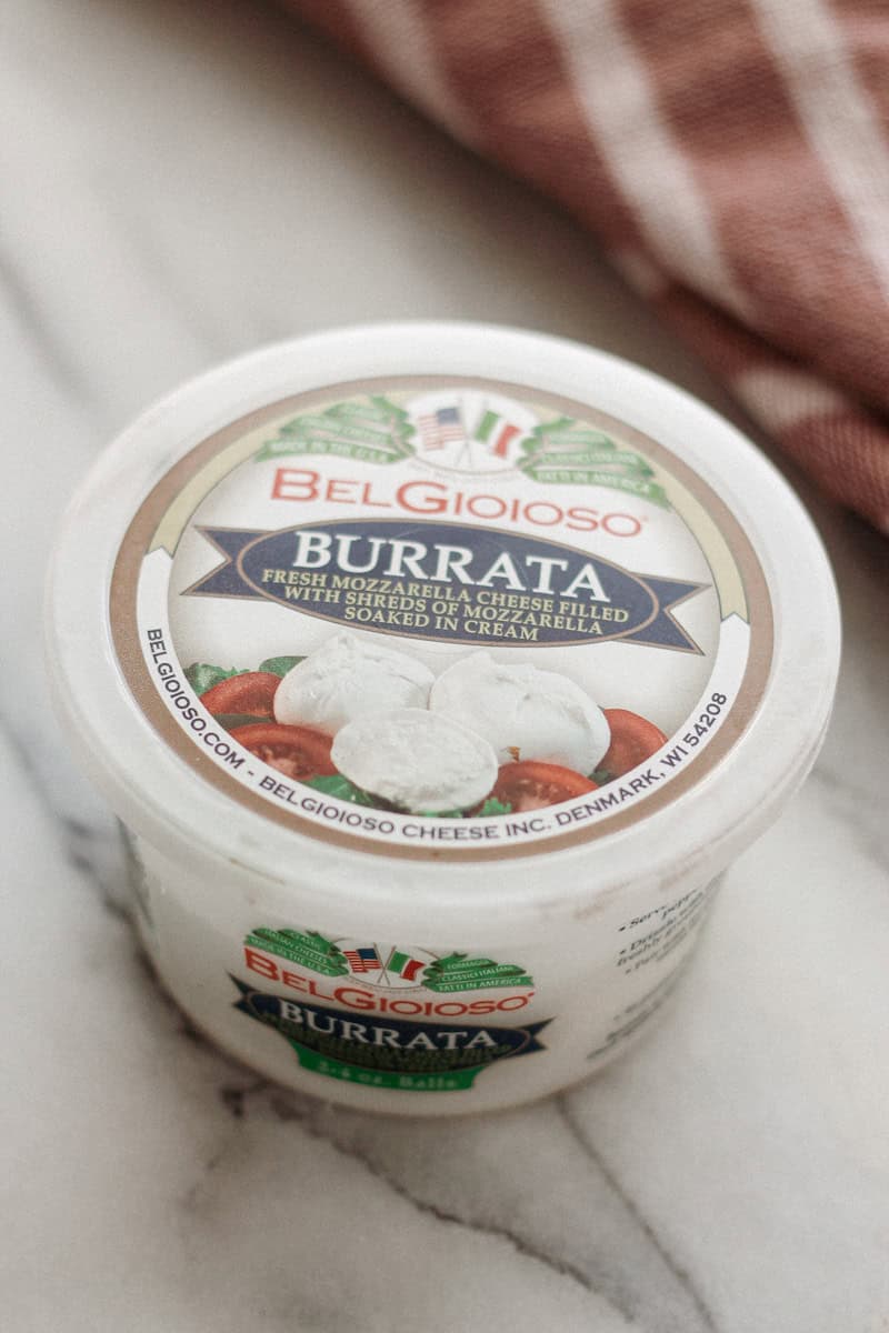Container of burrata cheese on kitchen counter.