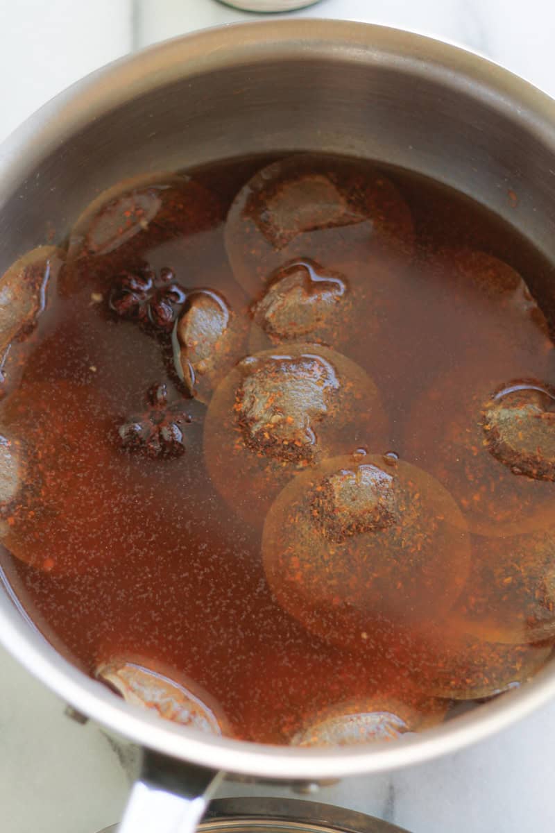 Rooibos tea with spices steeping in a stainless steel saucepan.