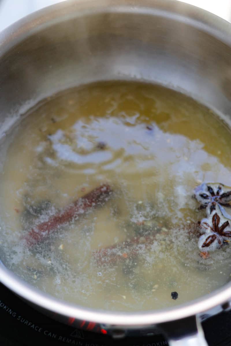 Spices and minced ginger simmering in a saucepan.